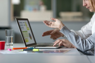 Hands gesturing discussion over a laptop. 