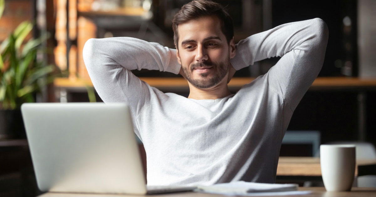 A man relaxed back while sat in front of a laptop.